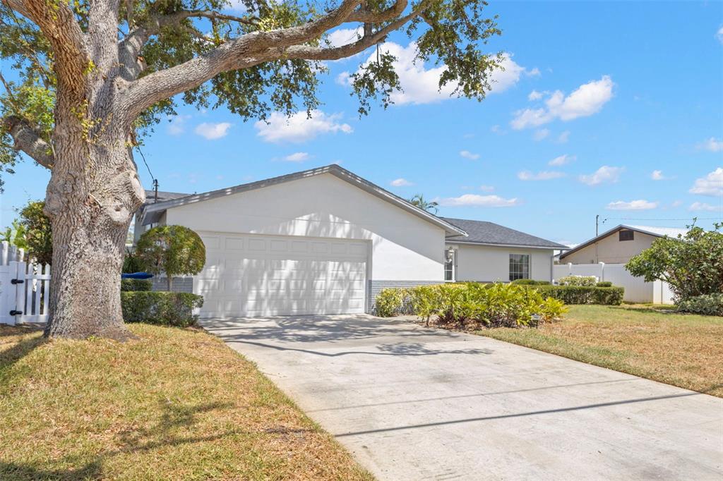 A single-story house with a white exterior, a two-car garage, and a large front tree — 4960 DOVER STREET NE, ST PETERSBURG, FL