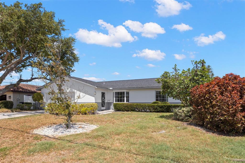 A single-story white house with a dark roof, a front lawn, and mature landscaping — 4960 DOVER STREET NE, ST PETERSBURG, FL