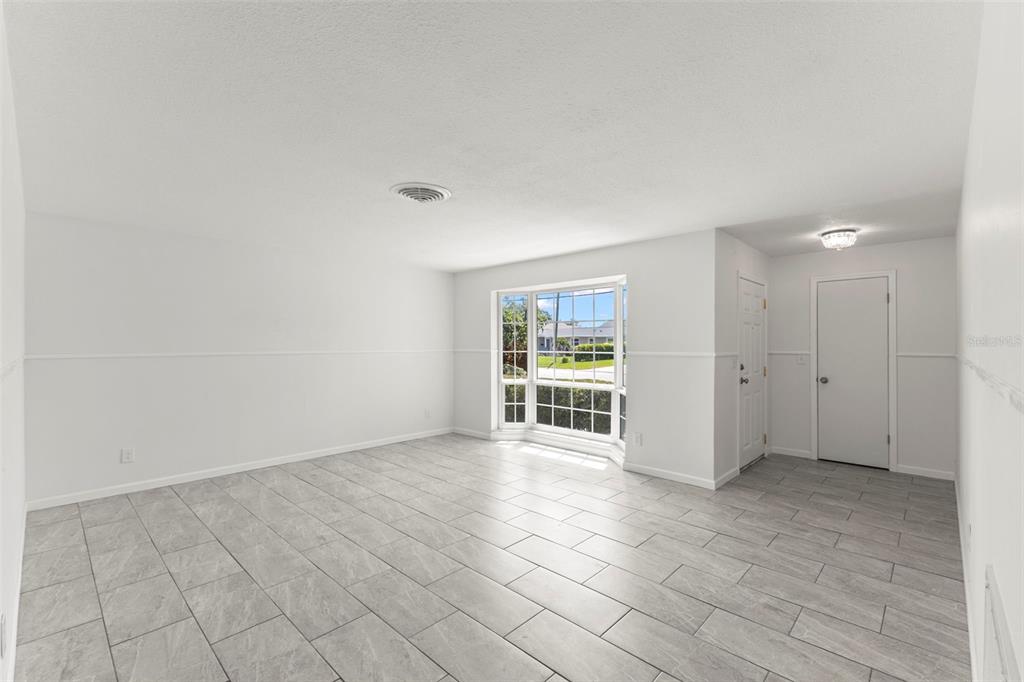 A bright, empty room features gray tile flooring, white walls, and a large bay window — 4960 DOVER STREET NE, ST PETERSBURG, FL