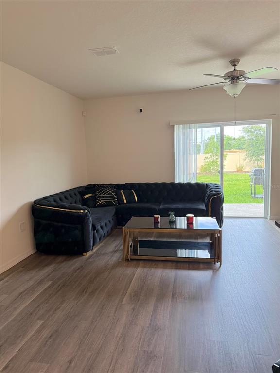 A living room features a black tufted sectional sofa, a glass coffee table, and sliding doors — 1217 BALSAM DRIVE, DAVENPORT, FL