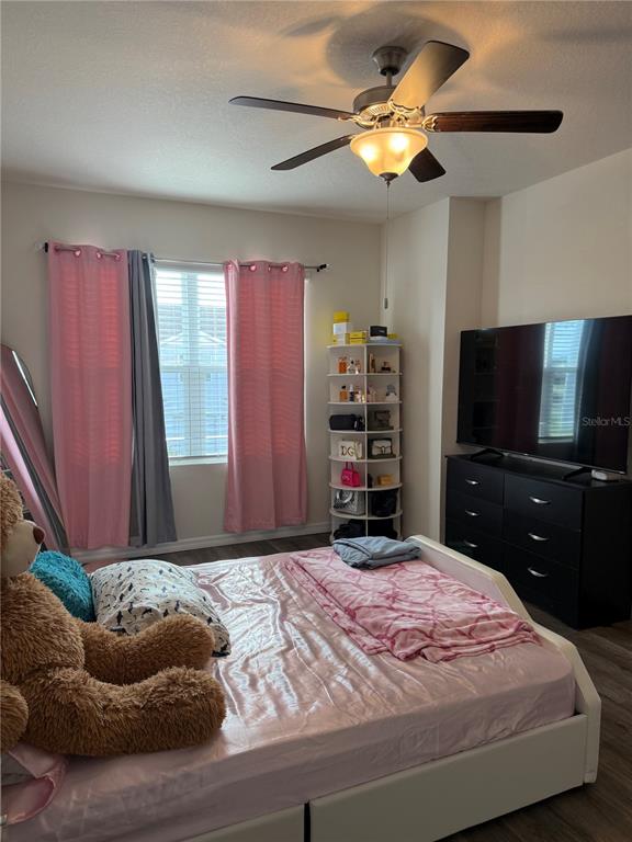 A bedroom features a bed with pink bedding, a ceiling fan, and a television stand — 1217 BALSAM DRIVE, DAVENPORT, FL