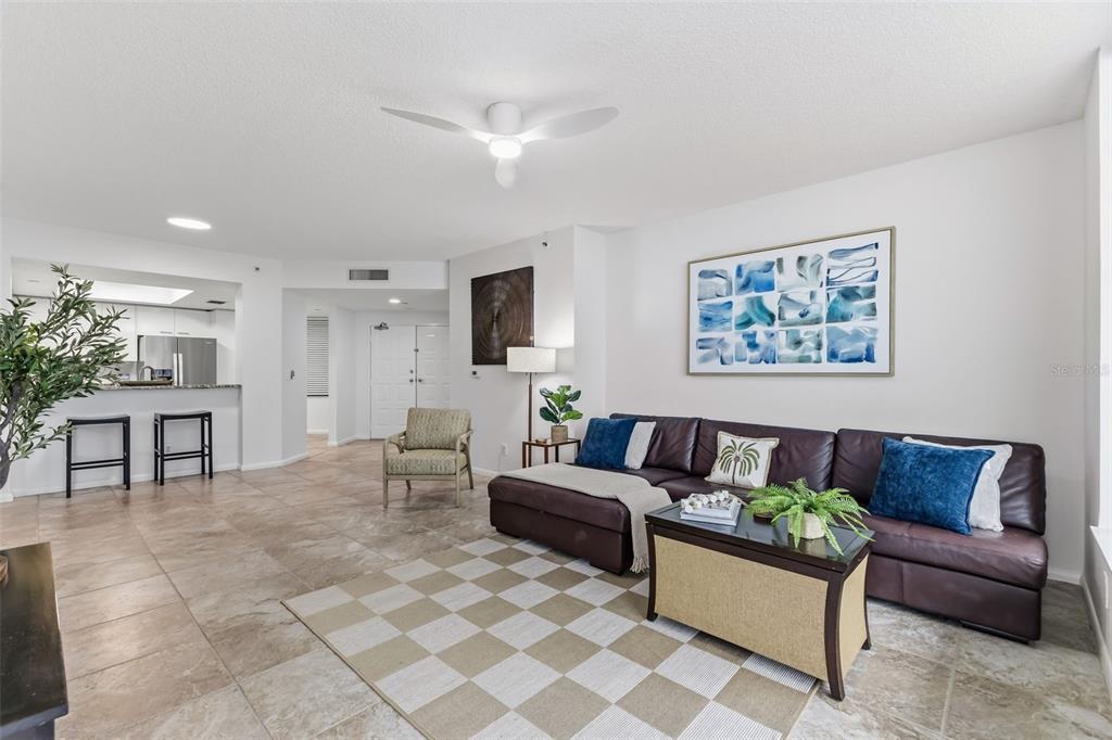A living room features a brown leather sectional, a checkered rug, and a kitchen counter — 1540 GULF BOULEVARD UNIT 1004, CLEARWATER BEACH, FL