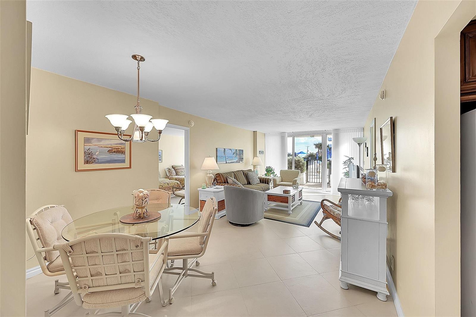 An open-concept living and dining area features tile flooring, a glass table, and balcony access — 531 N Ocean Boulevard # 410, Pompano Beach FL 33062, POMPANO BEACH, FL