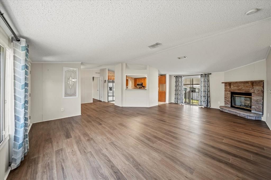 A spacious living room features wood-look flooring, a stone fireplace, and an open kitchen pass-through — 101 EDGEWOOD BOULEVARD, LAKE WALES, FL