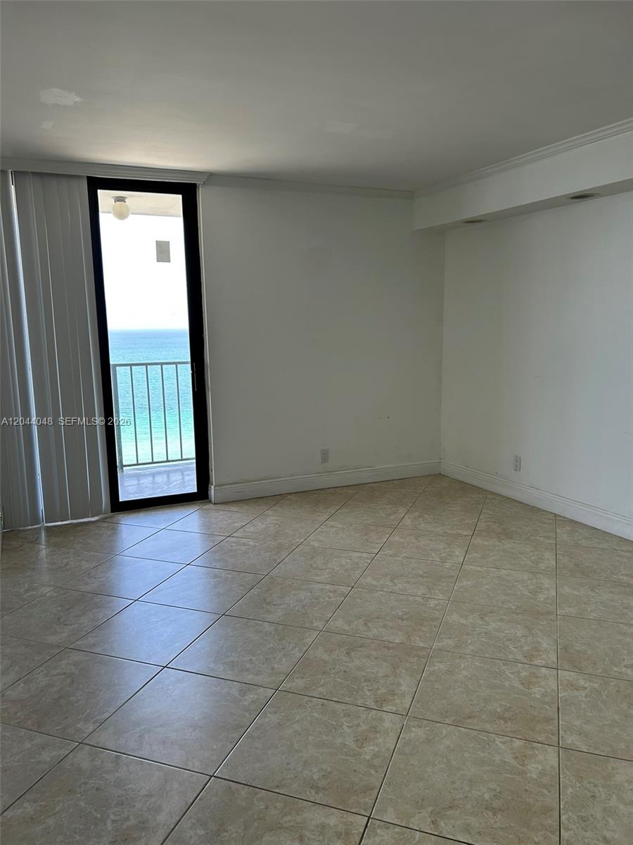 An empty room features beige tile flooring, white walls, and a glass door leading outside — 2625 Collins Ave # 1805, Miami Beach FL 33140, MIAMI BEACH, FL