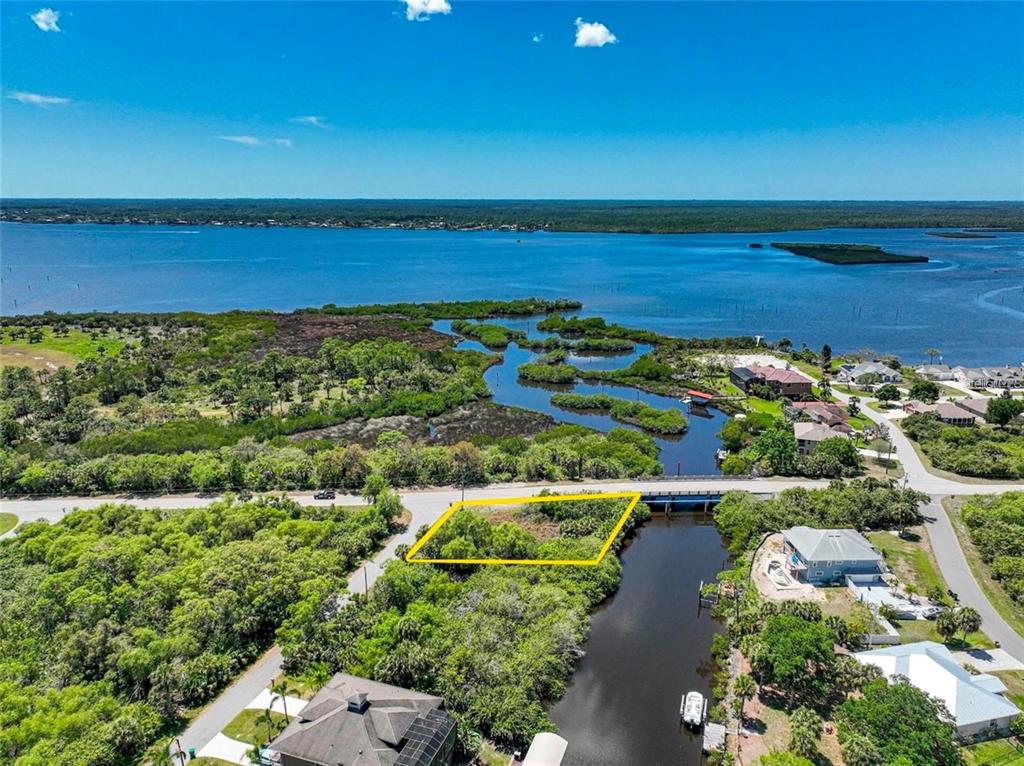 An aerial view shows a rectangular vacant lot bordered by a road and a canal — 12412 EISENHOWER DRIVE, PORT CHARLOTTE, FL