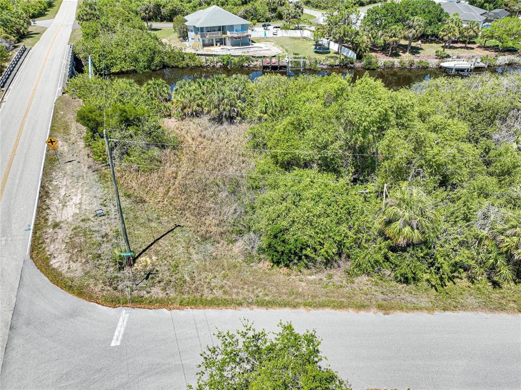 An aerial view shows a vacant, wooded lot situated between a road and a canal — 12412 EISENHOWER DRIVE, PORT CHARLOTTE, FL