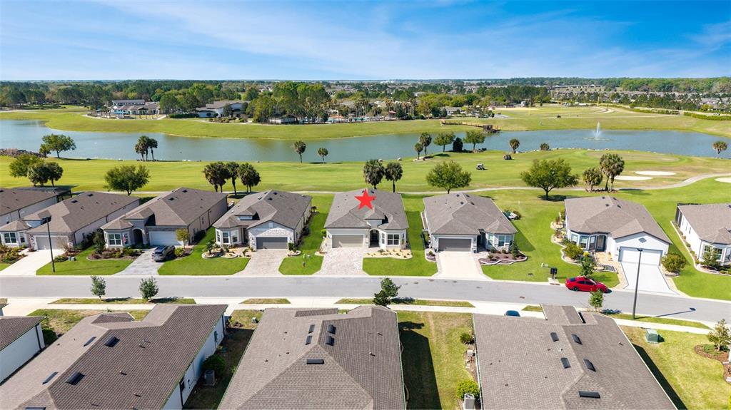 An aerial view shows a row of suburban houses overlooking a golf course and lake — 5702 SW 90TH COURT ROAD, OCALA, FL