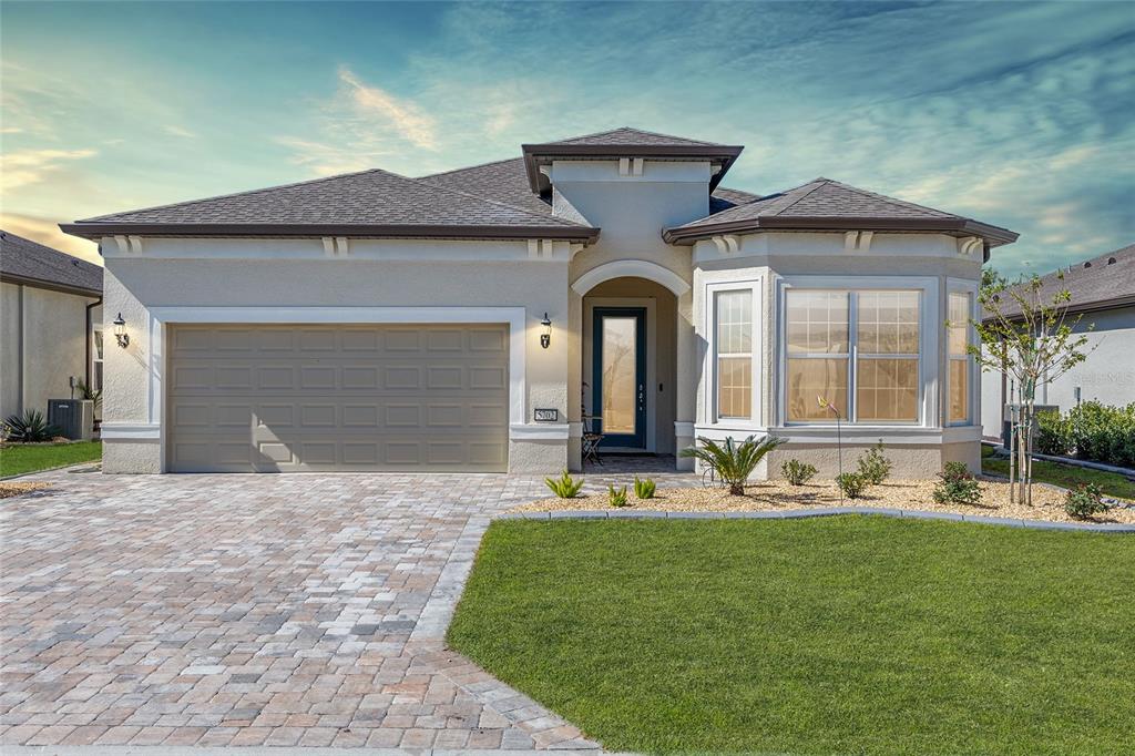 A single-story house with a beige stucco exterior, a two-car garage, and a paved driveway — 5702 SW 90TH COURT ROAD, OCALA, FL