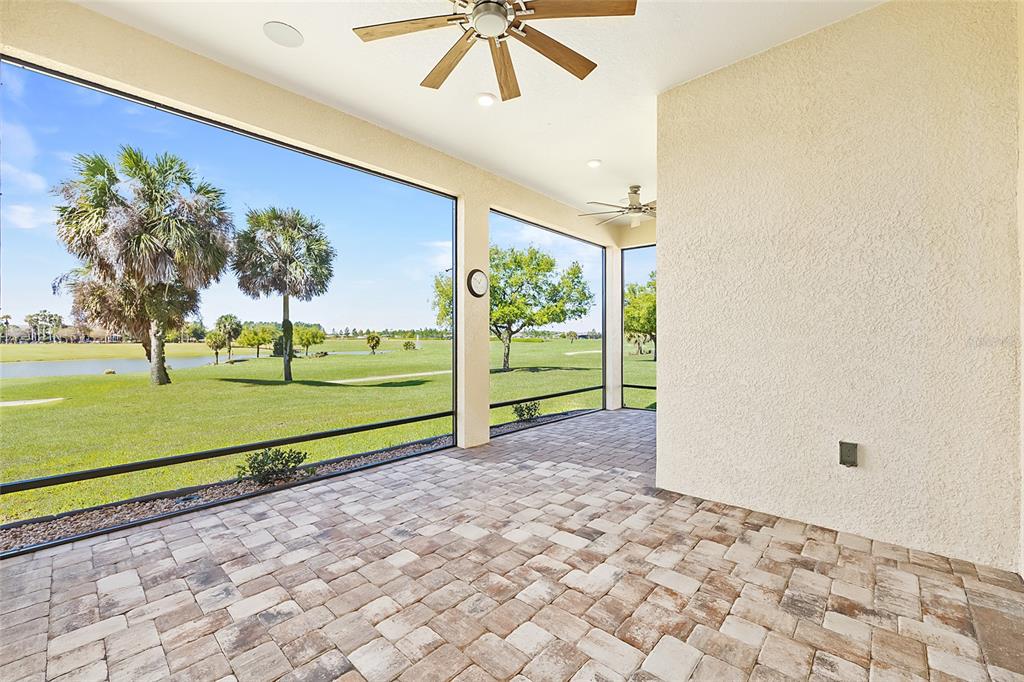 A covered patio with paver flooring overlooks a golf course through a screened enclosure — 5702 SW 90TH COURT ROAD, OCALA, FL