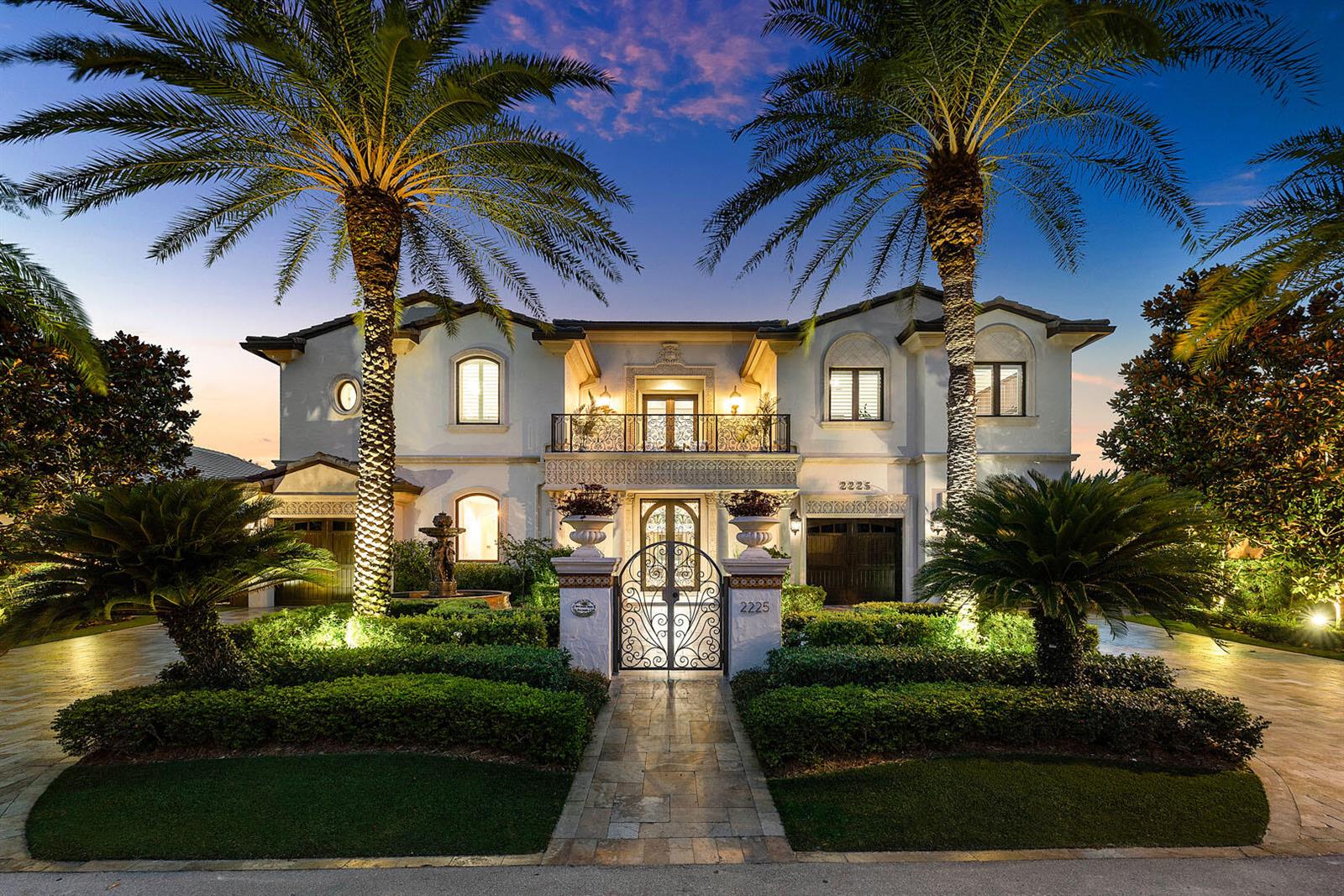 A two-story Mediterranean-style house features a gated courtyard, palm trees, and manicured landscaping at dusk — 2225 W Silver Palm Road, Boca Raton FL 33432, BOCA RATON, FL