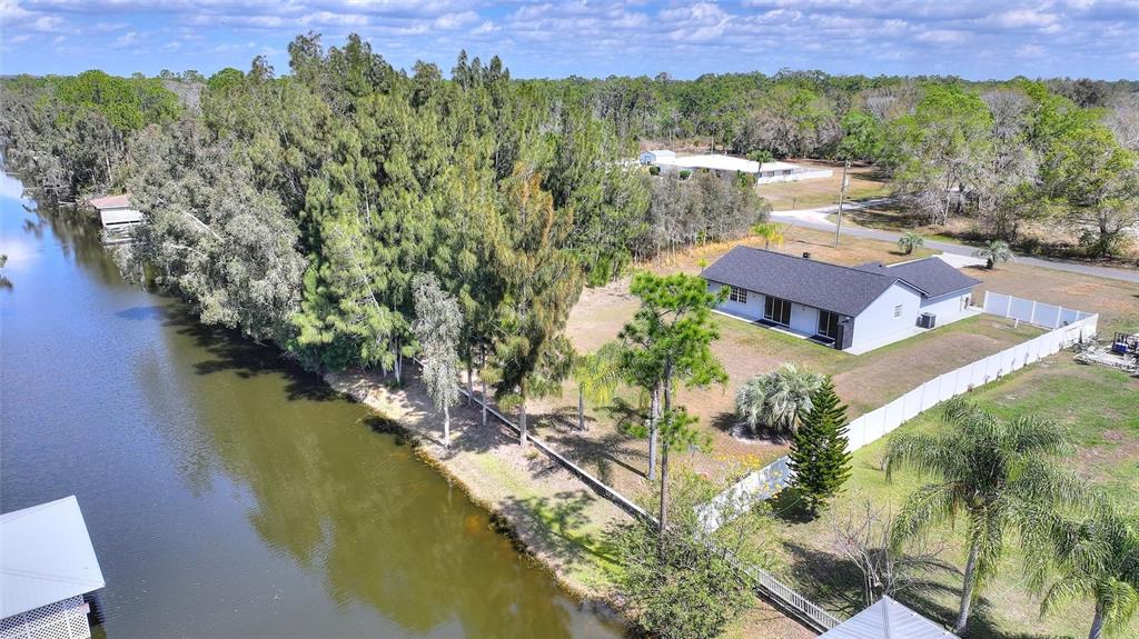 An aerial view shows a house with a dark roof situated beside a canal — 6294 ARBOREA DRIVE, INDIAN LAKE ESTATES, FL