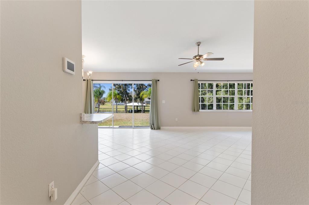 A bright living area features white tile flooring, a ceiling fan, and sliding glass doors — 6294 ARBOREA DRIVE, INDIAN LAKE ESTATES, FL