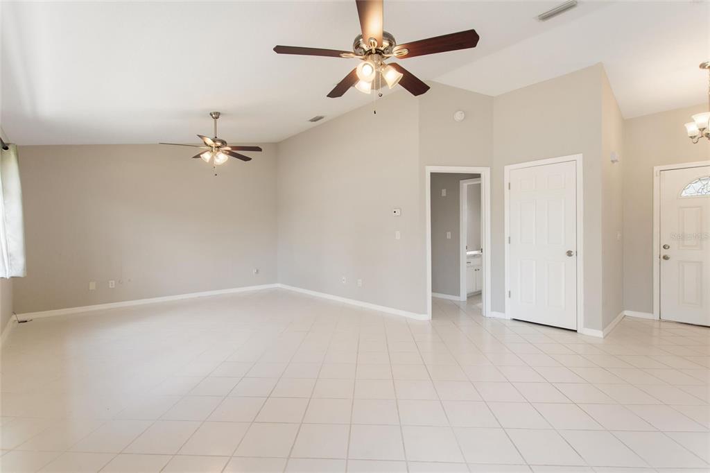 A spacious living room features light tile flooring, vaulted ceilings, and two ceiling fans — 6294 ARBOREA DRIVE, INDIAN LAKE ESTATES, FL