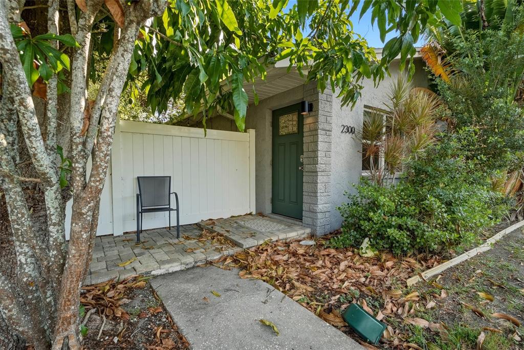 A green front door with a brick-style pillar stands beside a white privacy fence — 2310 29TH STREET N, ST PETERSBURG, FL