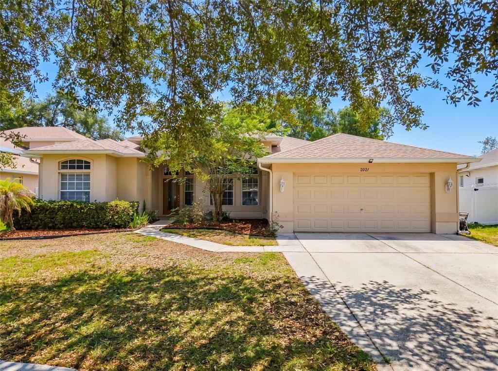 A single-story suburban house with a tan stucco exterior and a two-car garage — 2021 RUTHERFORD DRIVE, DOVER, FL