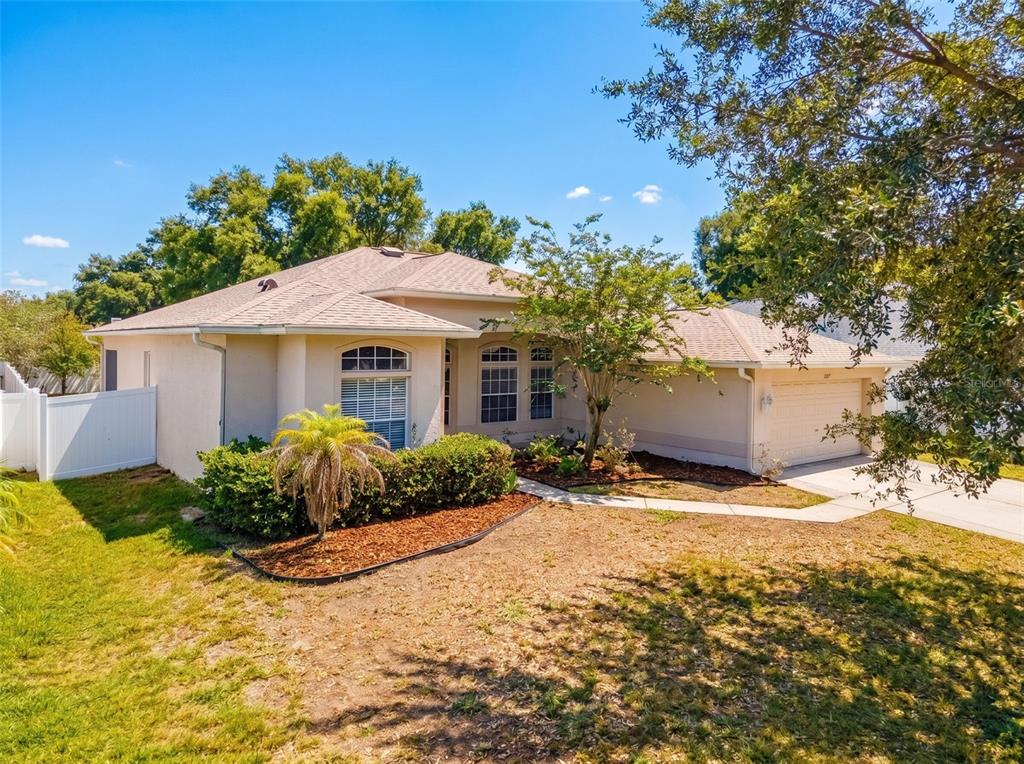 A single-story beige house with a two-car garage and a landscaped front yard — 2021 RUTHERFORD DRIVE, DOVER, FL