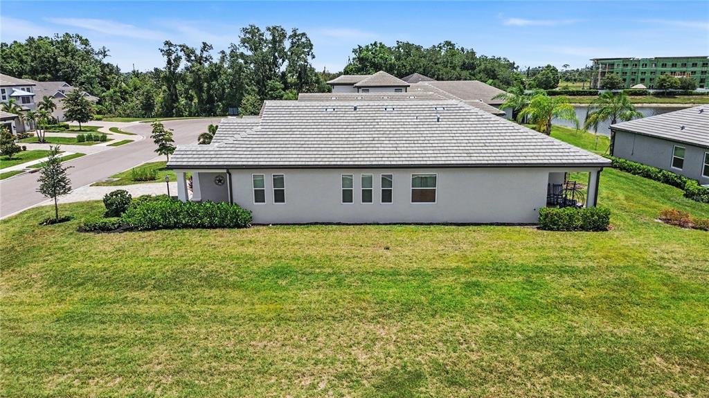 An exterior view of a single-story house with a gray tile roof and lawn — 12115 BALD CYPRESS COVE, PARRISH, FL