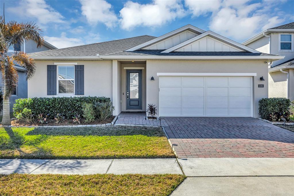 A single-story house with a beige exterior, a two-car garage, and a brick paver driveway — 3393 BLUFF OAK LANE, SANFORD, FL