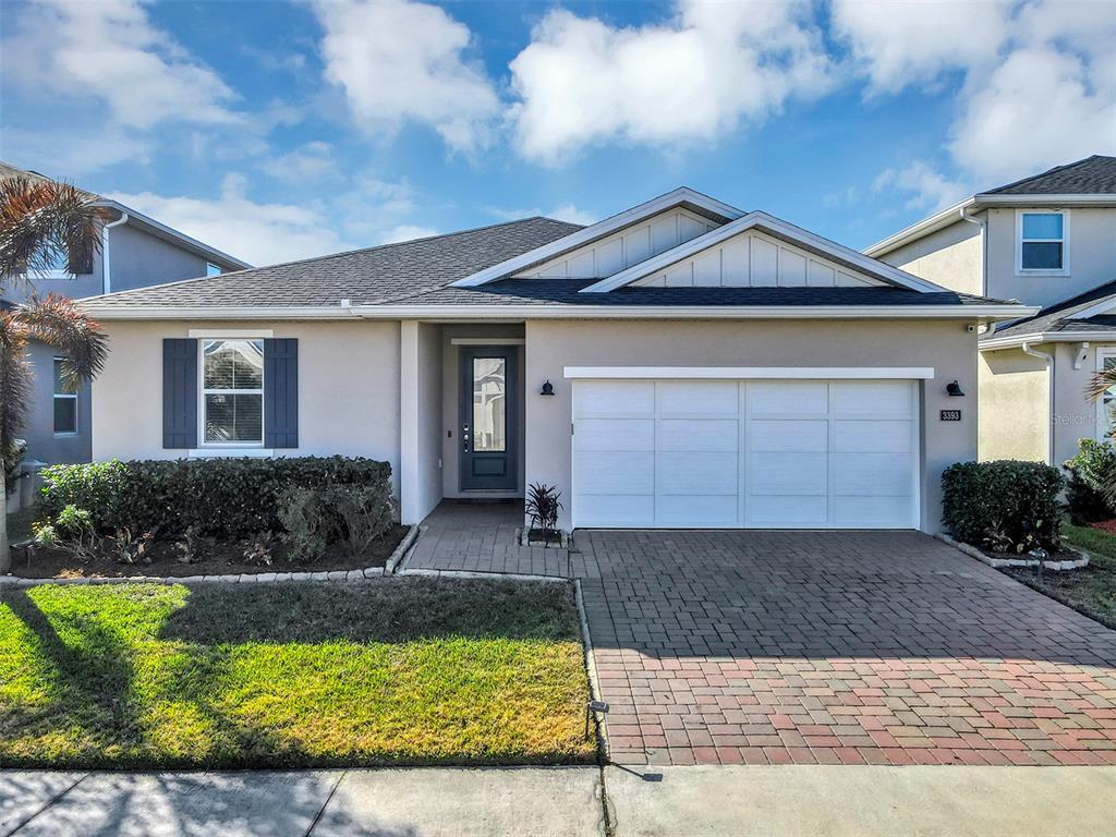 A single-story house with a white garage door, a gray front door, and a brick driveway — 3393 BLUFF OAK LANE, SANFORD, FL