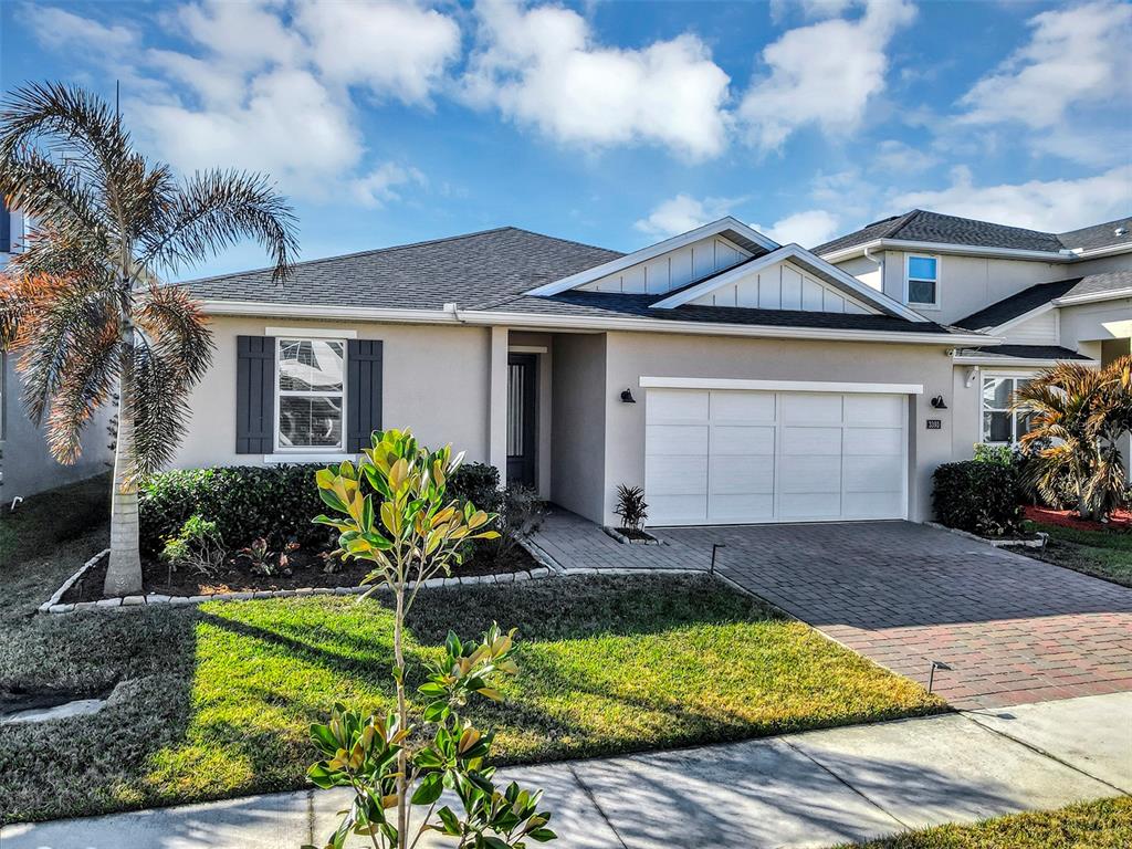 A single-story house with a white garage, dark shutters, and a palm tree in front — 3393 BLUFF OAK LANE, SANFORD, FL
