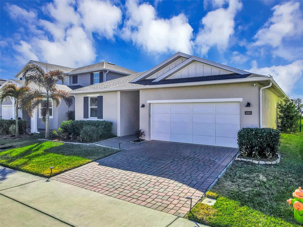 A single-story house with a white garage door, a paved driveway, and a palm tree — 3393 BLUFF OAK LANE, SANFORD, FL