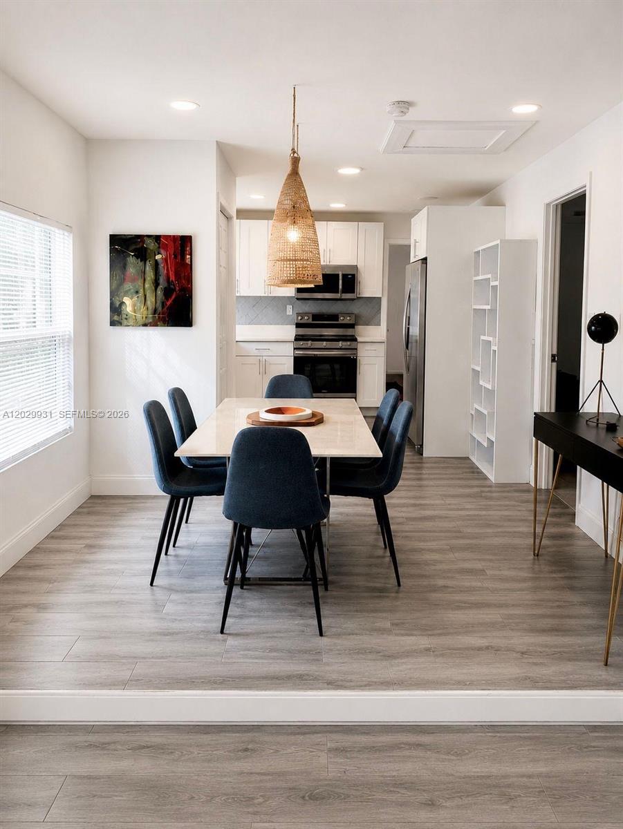 A dining area with a table, six blue chairs, and a pendant light near a kitchen — 5519 NW 4th Ave, Miami FL 33127, MIAMI, FL