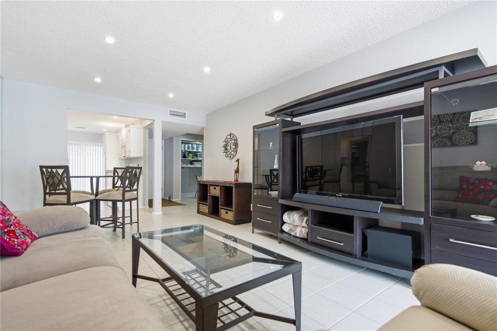 A living room features a large entertainment center, a glass coffee table, and tile flooring — 2052 SUNSET POINT ROAD UNIT 45, CLEARWATER, FL