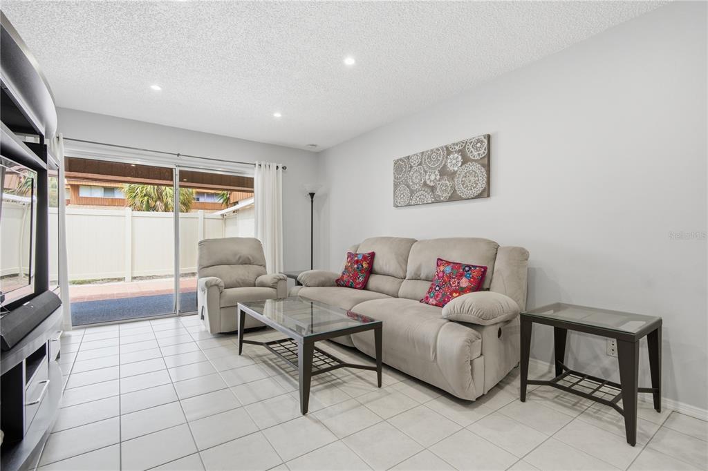 A living room features light tile floors, a beige sofa, a recliner, and sliding glass doors — 2052 SUNSET POINT ROAD UNIT 45, CLEARWATER, FL