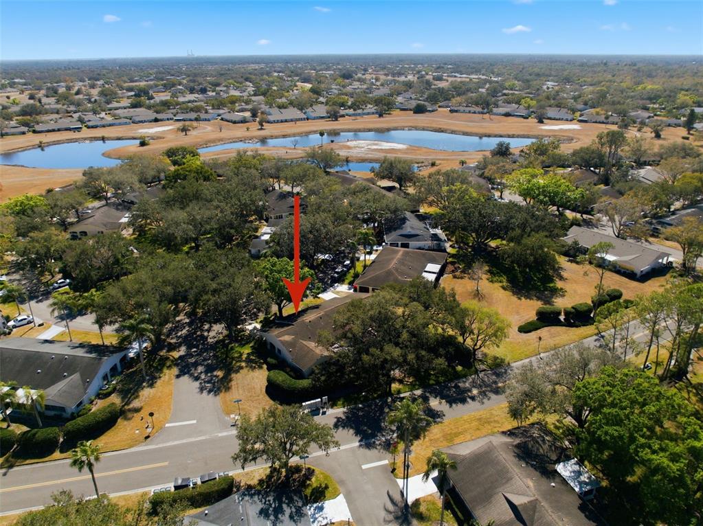 An aerial view shows a residential house with a red arrow pointing to its roof — 2101 HAILSTONE CIRCLE UNIT 0, SUN CITY CENTER, FL