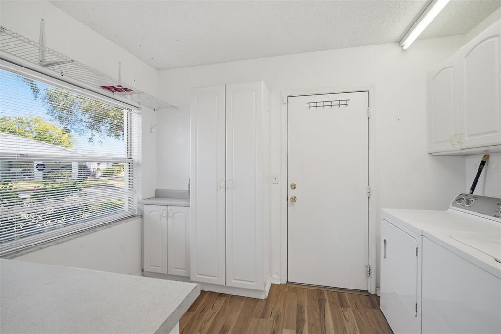 A laundry room features white cabinets, a window with blinds, and a white exterior door — 2101 HAILSTONE CIRCLE UNIT 0, SUN CITY CENTER, FL