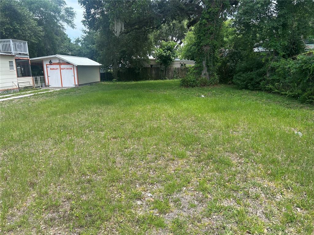 A grassy backyard features a small detached garage with Harley-Davidson branding on the doors — 147 KINGSTON AVENUE, DAYTONA BEACH, FL