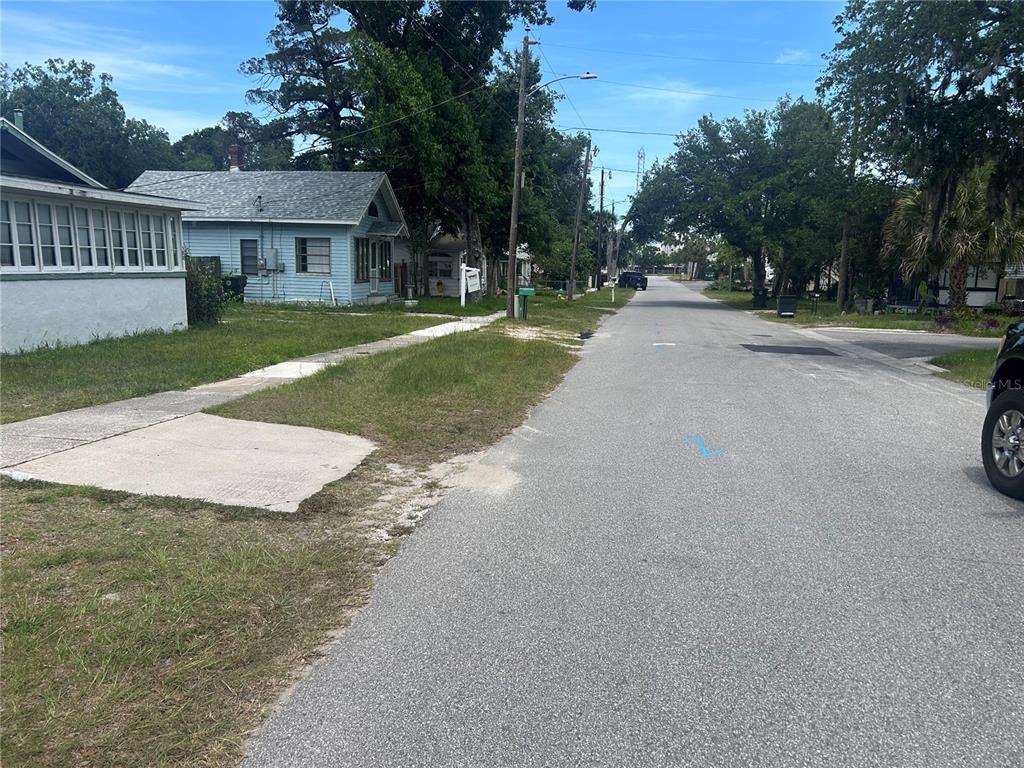A view of a residential street with a light blue house on the left — 147 KINGSTON AVENUE, DAYTONA BEACH, FL