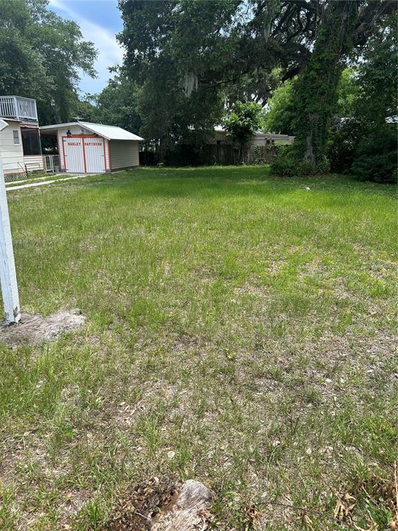A grassy vacant lot features a detached garage with Harley-Davidson branding in the background — 147 KINGSTON AVENUE, DAYTONA BEACH, FL