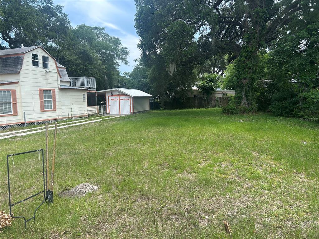 A grassy lot sits next to a white house with a detached garage — 147 KINGSTON AVENUE, DAYTONA BEACH, FL