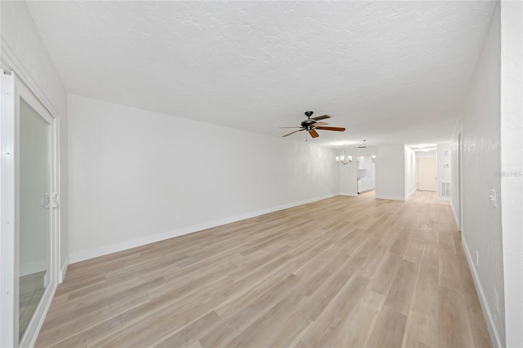 An empty living room features light wood-look flooring, white walls, and a ceiling fan — 285 BOCA CIEGA POINT BOULEVARD N UNIT 3009, ST PETERSBURG, FL