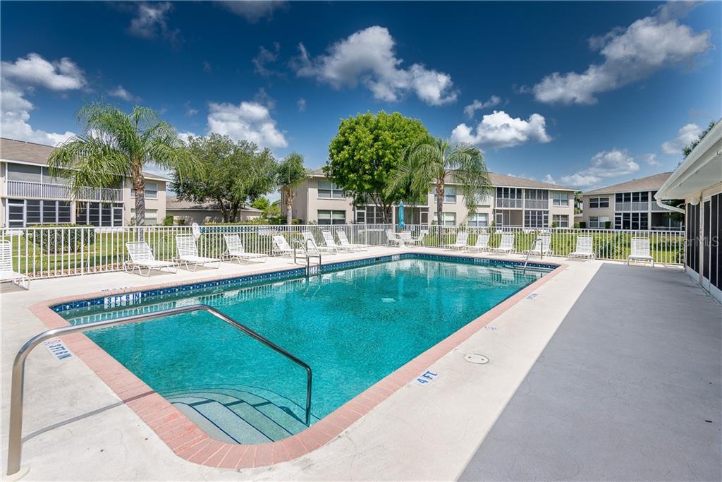 A rectangular swimming pool with a shallow entry area is surrounded by a concrete deck — 11644 SW EGRET CIRCLE UNIT 506, LAKE SUZY, FL