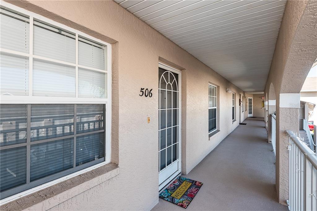 An exterior walkway leads to the front door of a residential unit numbered 506 — 11644 SW EGRET CIRCLE UNIT 506, LAKE SUZY, FL
