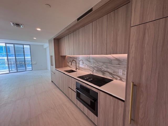 A modern kitchen features wood-grain cabinetry, a marble backsplash, and integrated appliances — 77 SE 5 ST # 1806, Miami FL 33131, MIAMI, FL