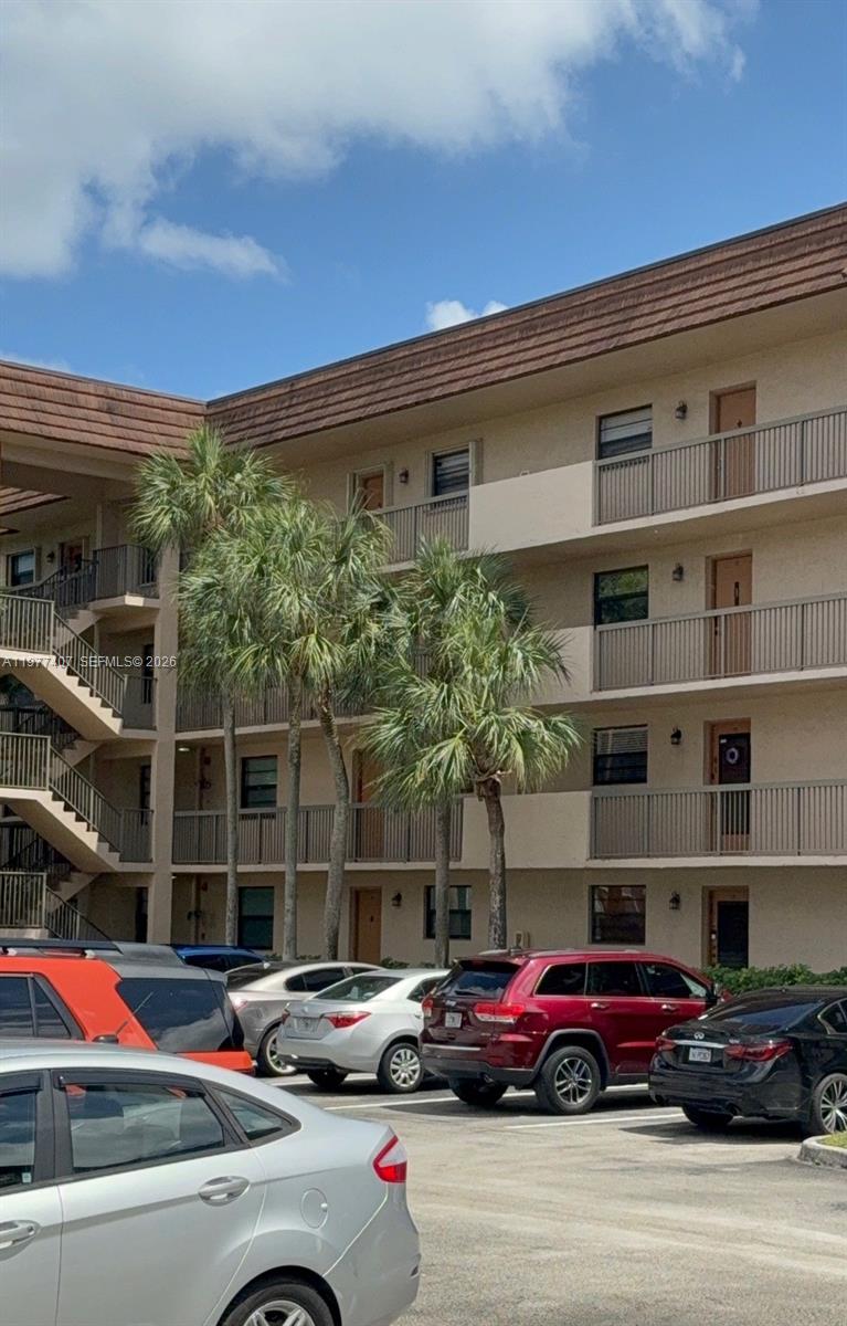 A multi-story apartment building exterior with balconies and a parking lot in the foreground — 4940 E Sabal Palm Blvd # 203, Tamarac FL 33319, TAMARAC, FL