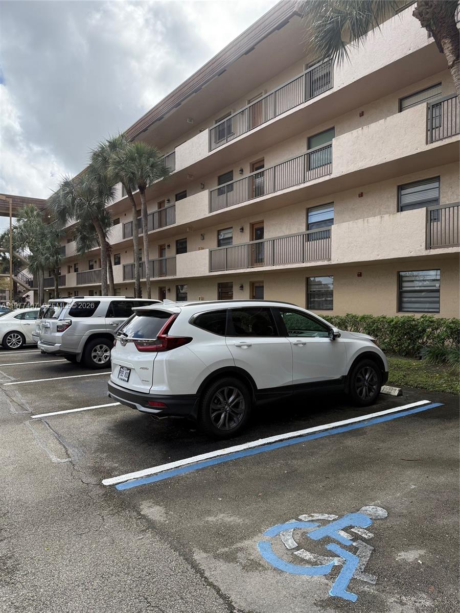 A multi-story apartment building exterior with a parking lot featuring a designated handicap space — 4940 E Sabal Palm Blvd # 203, Tamarac FL 33319, TAMARAC, FL