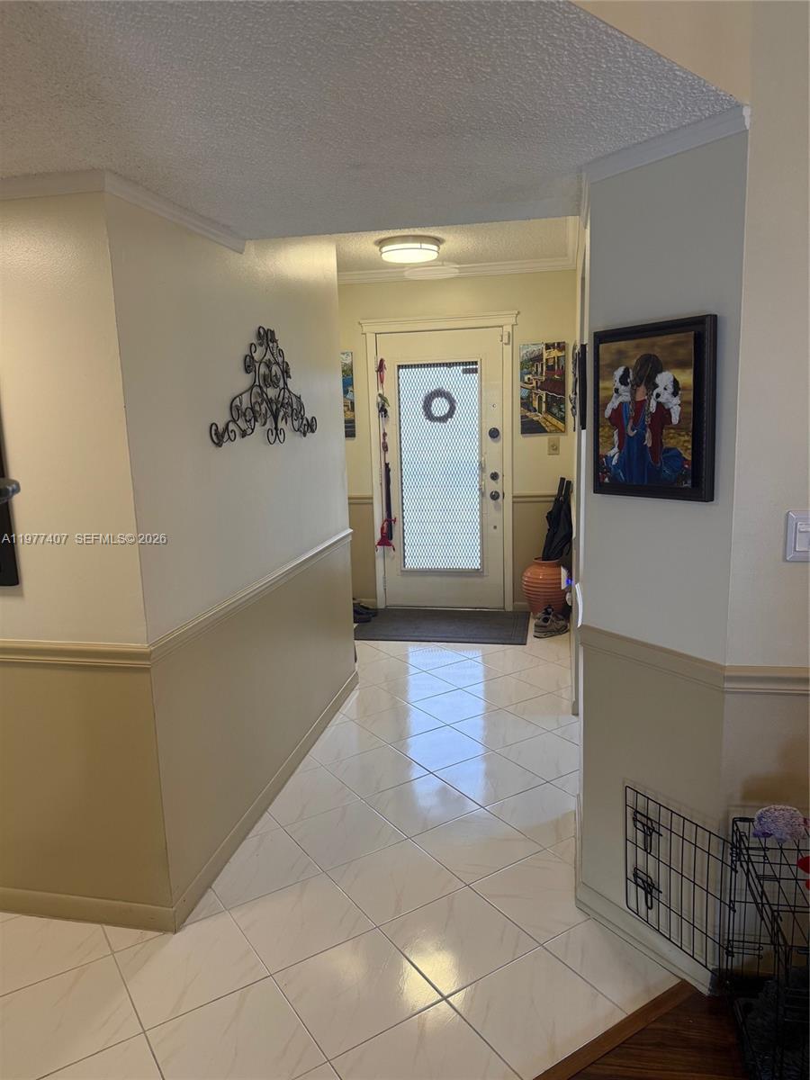 A tiled entryway features a white front door, wainscoting, and wall-mounted decor — 4940 E Sabal Palm Blvd # 203, Tamarac FL 33319, TAMARAC, FL