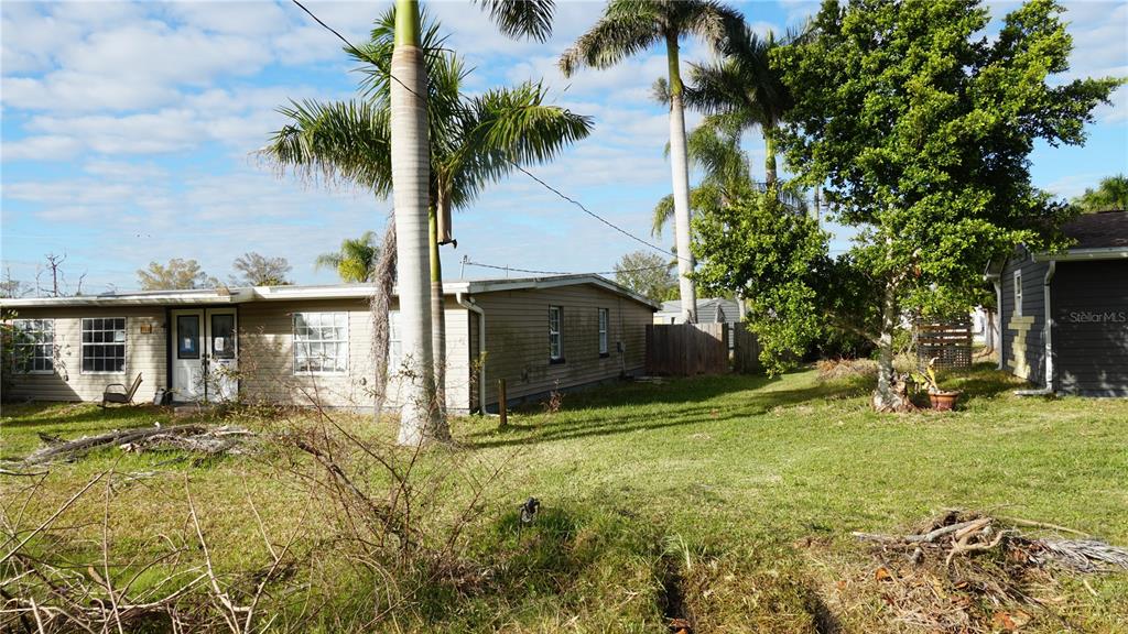 A single-story house with tan siding stands in a grassy yard with palm trees — 3513 ARECA STREET, PUNTA GORDA, FL