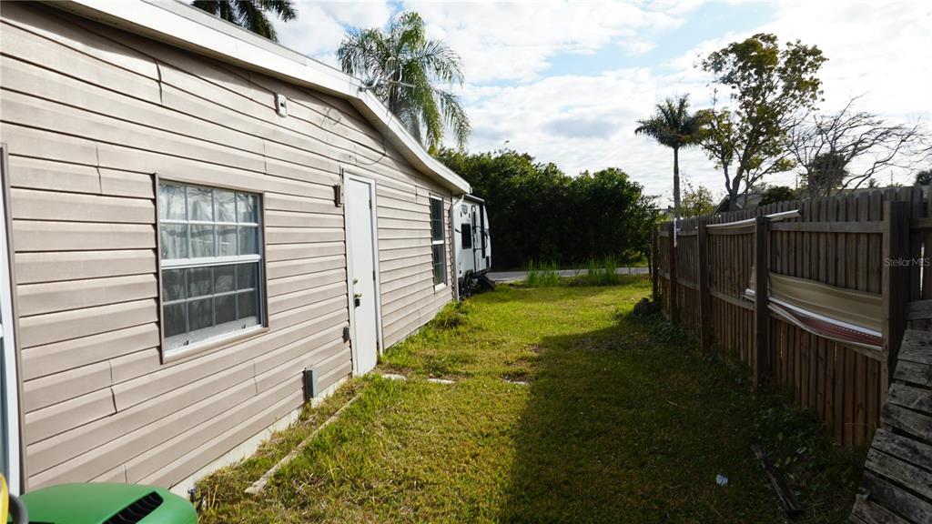 A side view of a house exterior with beige siding, a window, and a door — 3513 ARECA STREET, PUNTA GORDA, FL