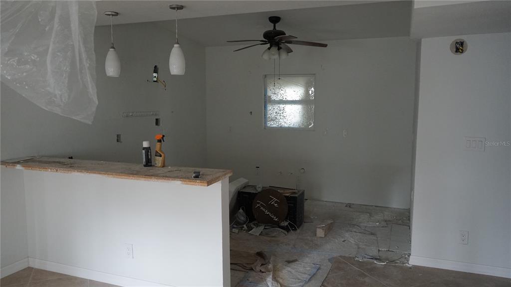 An unfinished kitchen features a breakfast bar, pendant lighting, a ceiling fan, and bare walls — 3513 ARECA STREET, PUNTA GORDA, FL