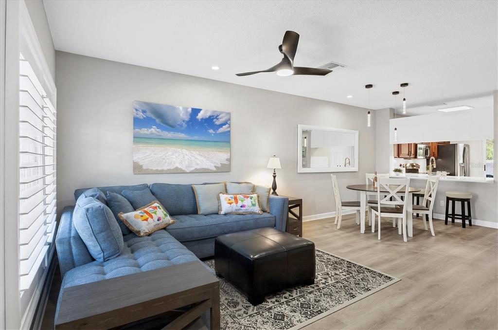 A living room with a blue sectional sofa, black ottoman, and an adjacent dining area — 4688 SABAL KEY DRIVE, BRADENTON, FL