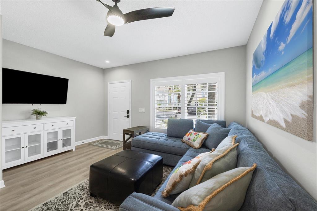 A living room features a blue sectional sofa, a black ottoman, and a white media console — 4688 SABAL KEY DRIVE, BRADENTON, FL