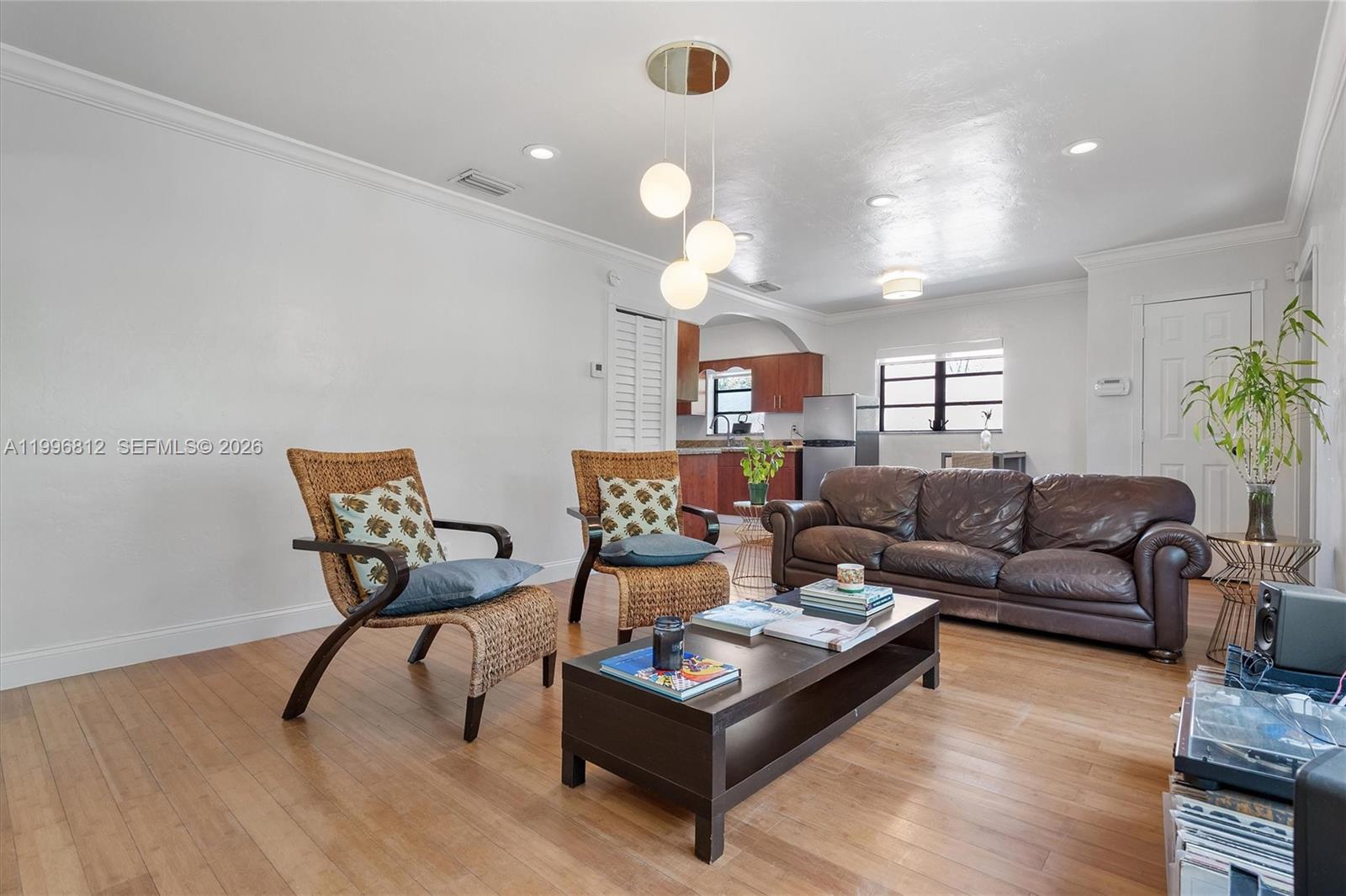 A living room features hardwood floors, a brown leather sofa, two wicker chairs, and a coffee table — 1440 NE 148th St, Miami FL 33161, MIAMI, FL