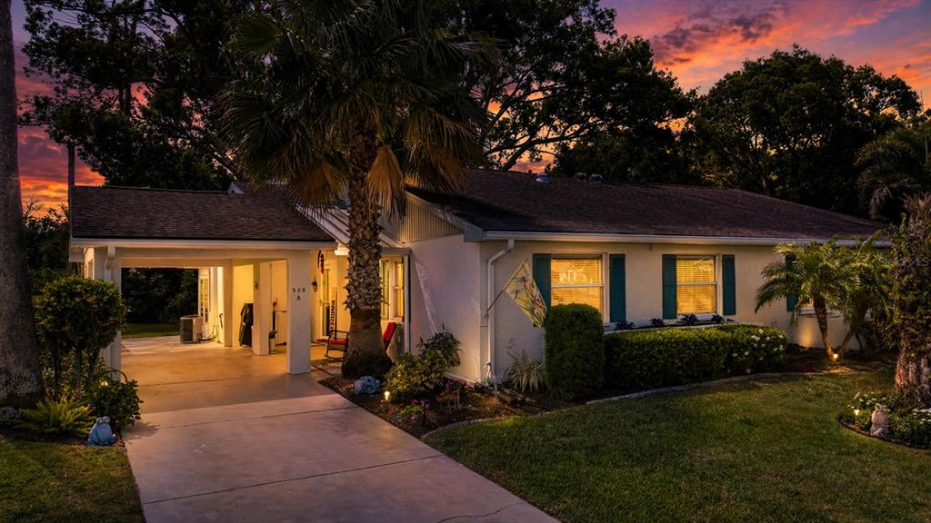 A single-story house with a carport and a palm tree at dusk — 505 FINSBURY CIRCLE UNIT A, SUN CITY CENTER, FL