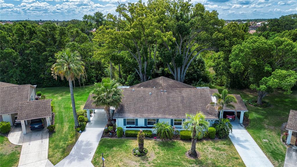 An aerial view shows a single-story house with a brown roof, two carports, and palm trees — 505 FINSBURY CIRCLE UNIT A, SUN CITY CENTER, FL